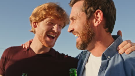 diverse group laughing hangout at rooftop close up. happy friends holding beer