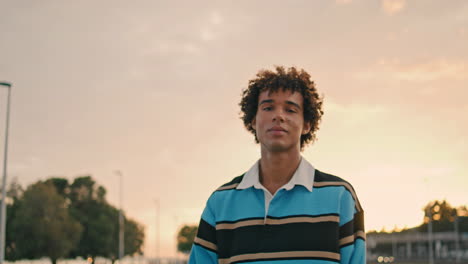 stylish student holding skate evening city portrait. man looking camera vertical