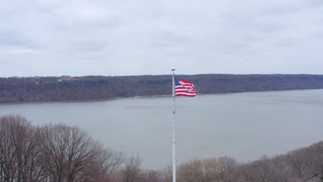 American-flag-waving-in-the-wind-near-Hudson-river,-New-York