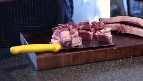 Close-up-of-male's-hands-slicing-raw-uncooked-meat-in-preparation-for-homemade-sausage