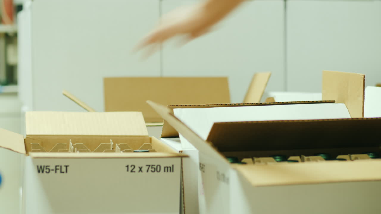 작업자는 상자에 와인 병을 포장합니다.