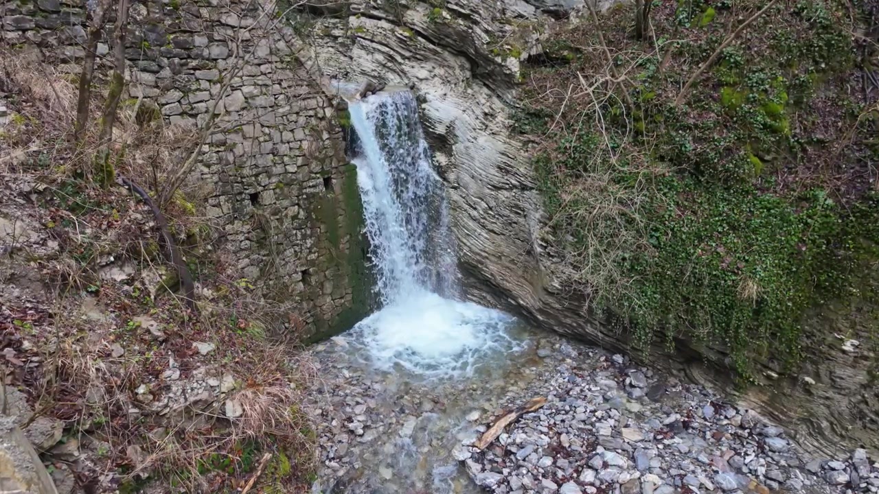 Gorges de Driselpoh près de Tolmin, Slovénie, avec une petite cascade sur la rivière Koritnica s'écoulant à travers des falaises rocheuses, de la mousse, des piscines naturelles claires et des arbres hivernaux dénudés dans la vallée alpine.