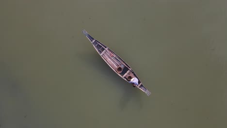 vista aérea hacia abajo de un pescador solitario en un barco de madera tradicional flotando en el río ichamati