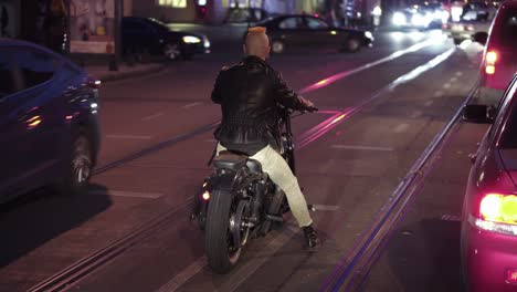 Rare-view-of-motorcyclist-drives-a-bike-in-the-city,-waiting-traffic-light-at-night