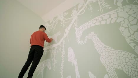 the artist is decorating walls by drawings in the children's room. art painting of the walls in the new house. repair works.