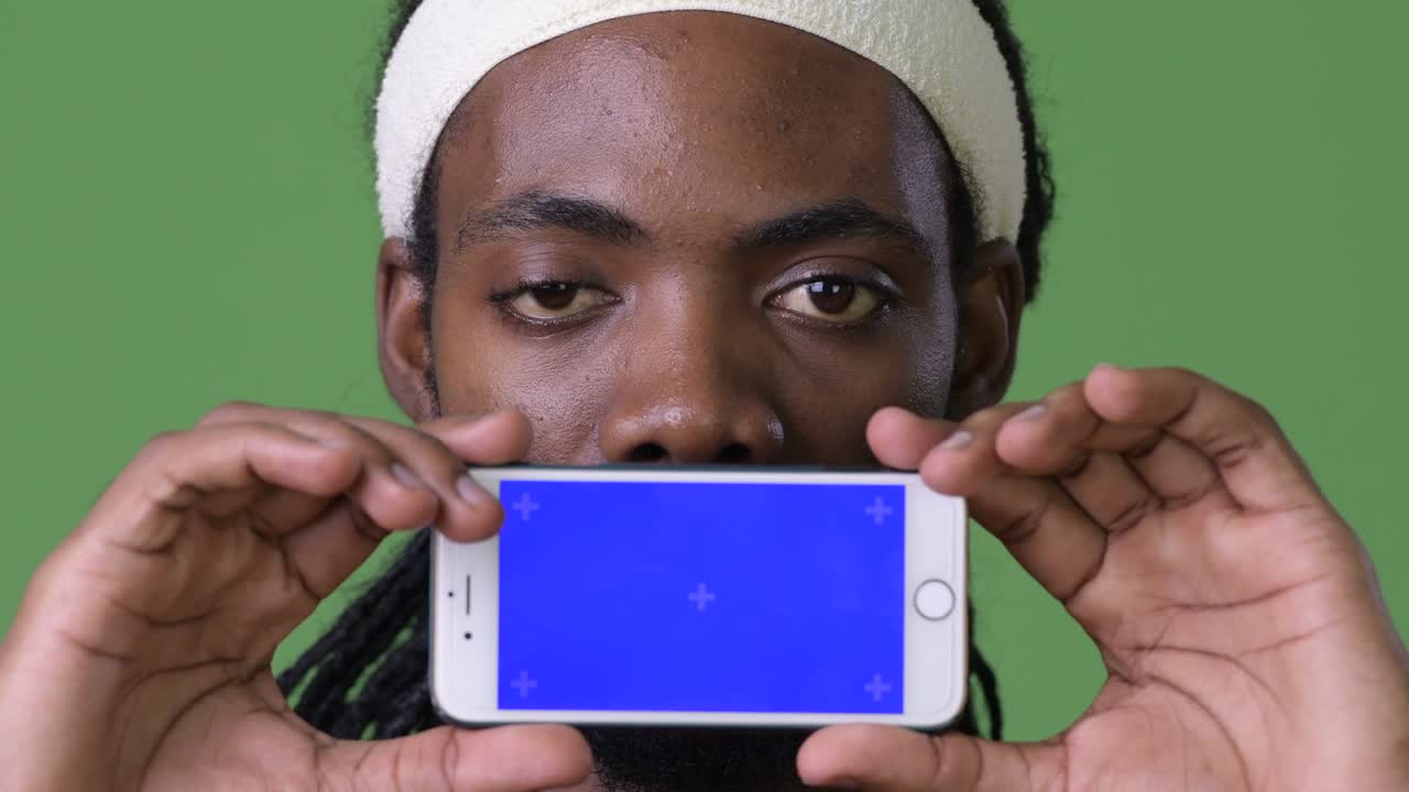 joven hombre africano guapo con dreadlocks contra un fondo verde
