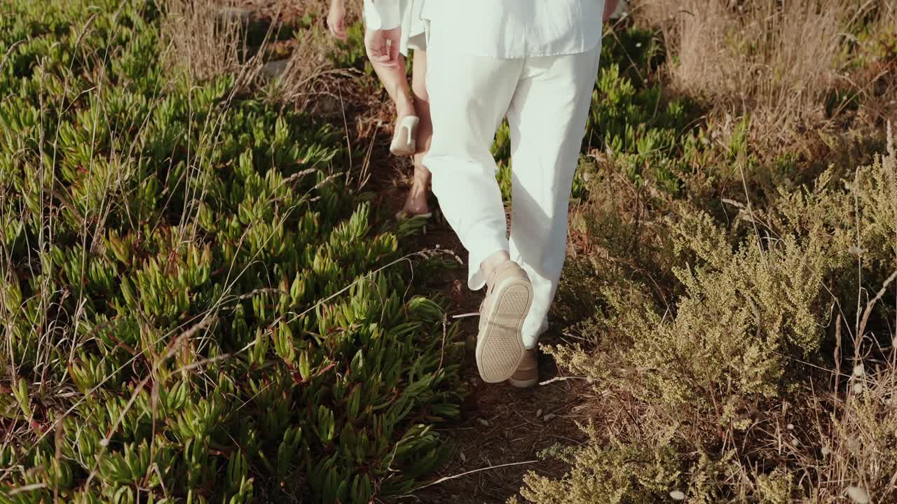 Closeup of couple walking on natural path surrounded by plants