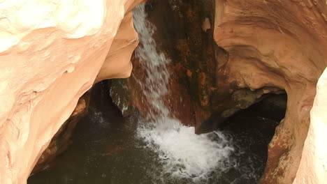 beautiful waterfall flows into natural pool surrounded by brown rock formation in national park tazakka , morocco