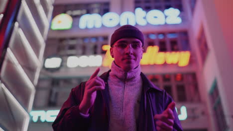 stylish man posing in a neon-lit city at night