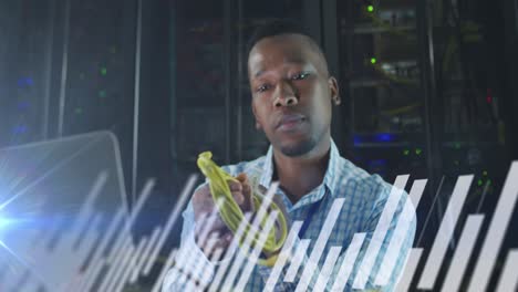 Animation-of-graphs-over-african-american-man-working-on-laptop-in-server-room