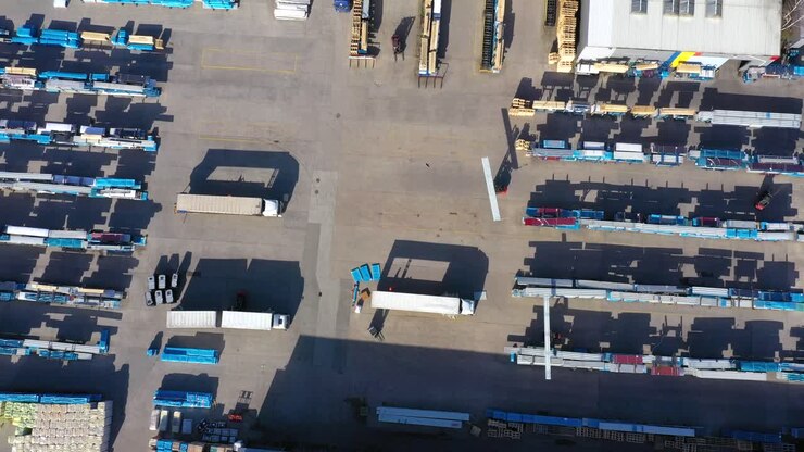 Trucks with semi-trailers stand on the parking lot of the logistics park with loading hub and wait for load and unload goods at warehouse ramps at sunset