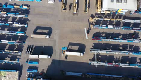Trucks with semi-trailers stand on the parking lot of the logistics park with loading hub and wait for load and unload goods at warehouse ramps at sunset