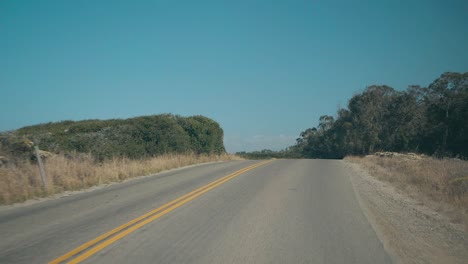 Slow-Motion-drive-on-winding-road-near-coast-on-bright-sunny-day