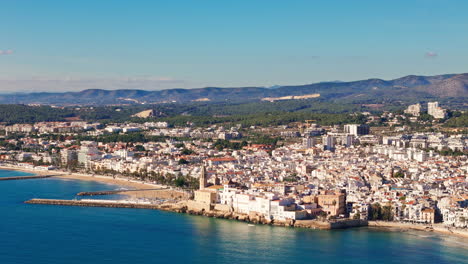 drone captures ancient coastal city in sunny weather with a mountain backdrop