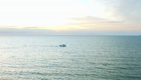 Fishing-Boat-Speeding-Along-Ocean-Surface-At-Sunrise-With-Colorful-Sky,-Aerial-4K-Drone