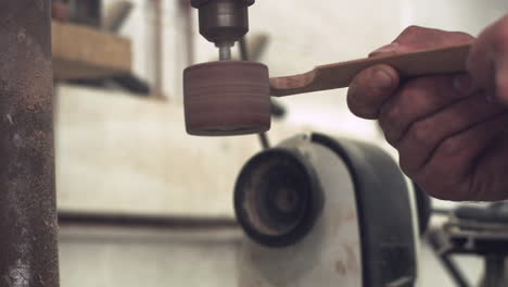 sliding pull back shot of a worker's hands using a sander to shape a piece of wood