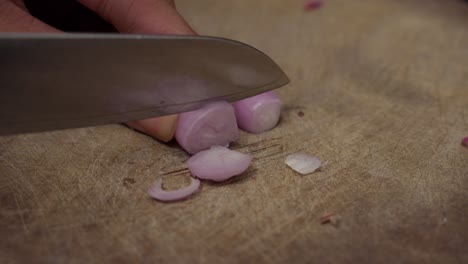 close-up of hands chopping red onions on a wooden cutting board