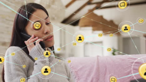 Animation-of-network-of-connections-with-icons-over-biracial-woman-talking-on-smartphone