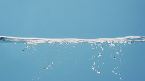 Vídeo-De-Una-Botella-De-Producto-De-Belleza-Emparedada-En-Agua-Con-Espacio-Para-Copiar-Sobre-Fondo-Azul