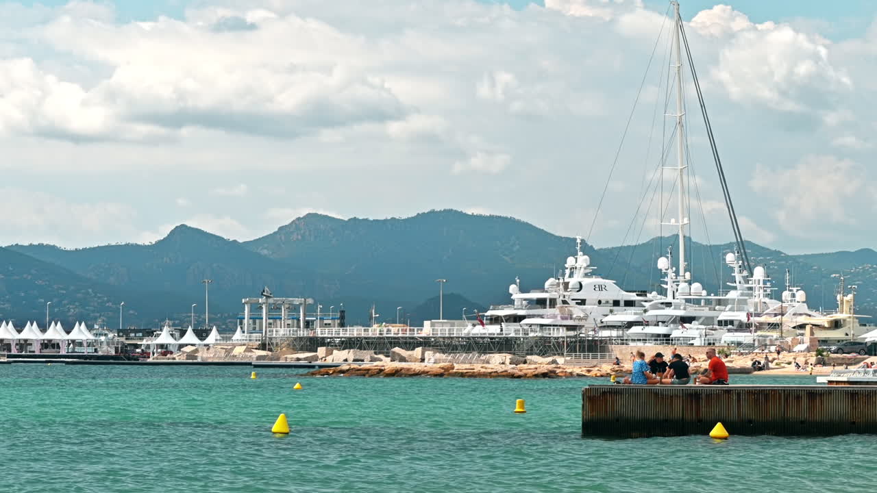 CANNES, FRANCE - AUGUST 28, 2021: View of the sea port with resting people on a pier, moored yachts
