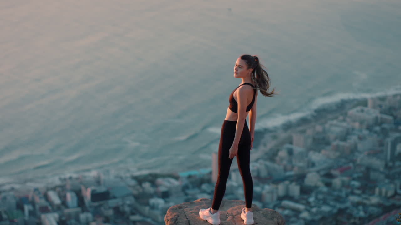 mujer independiente con los brazos levantados en la cima de la montaña celebrando el logro niña en el borde del acantilado mirando la hermosa vista al atardecer disfrutando de la aventura de viaje