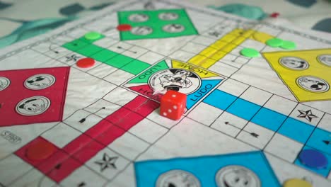 Hand-of-Man-throws-or-rolls-dice,-Indian-people-playing-Ludo-board-game-at-home-on-covid-19-coronavirus-lockdown,-shallow-focus,-slow-motion