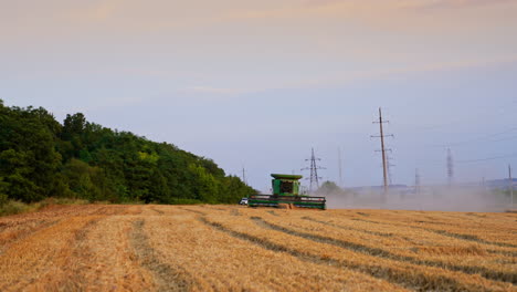 Harvesting wheat in an evening field. A combine harvester works diligently in a wheat field at dusk, creating clouds of dust as it moves along the rows