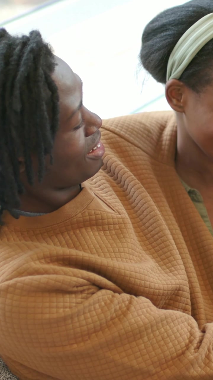 Vertical video: Talking man turning head to connect, she leaning in on couch at home, headband