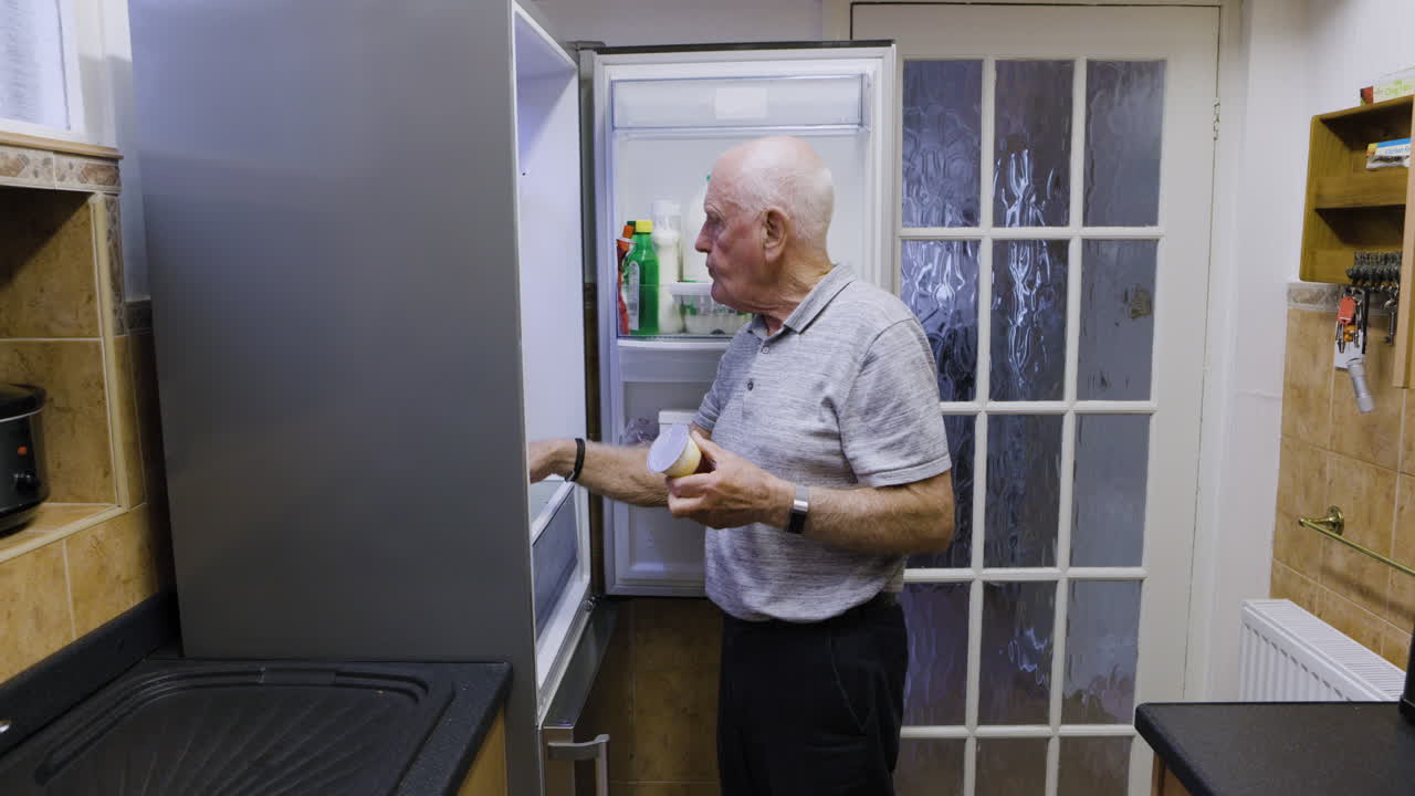 Elderly man looking in fridge in kitchen
