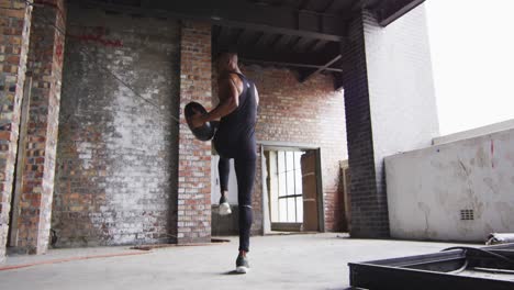 african american man exercising with medicine ball in an empty urban building