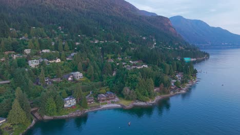an aerial sunset shot of luxury homes along lions bay, british columbia, canada with the brunswick mountains behind