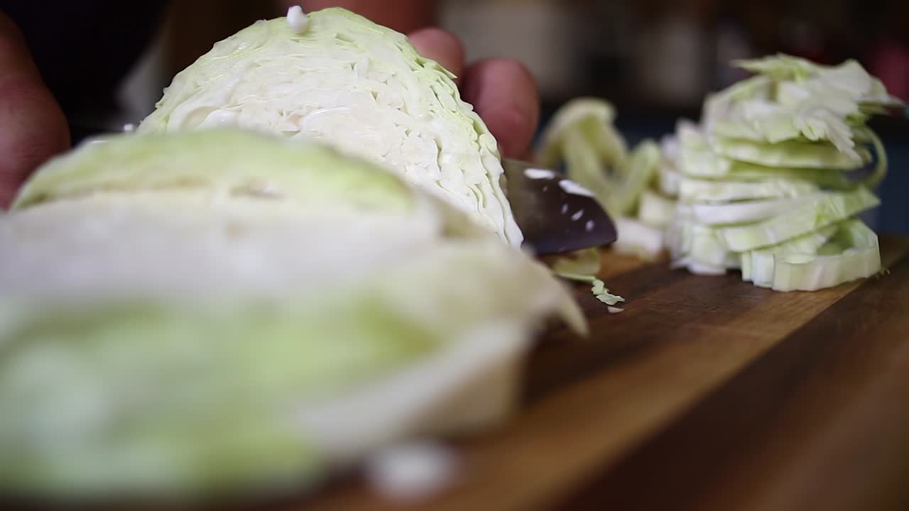 Close up detail: Hands with knife chop raw cabbage on cutting board
