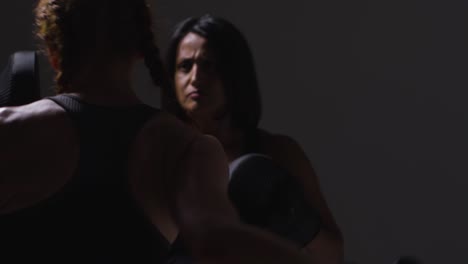fotografía de estudio de cerca de dos mujeres maduras con ropa de gimnasia haciendo ejercicio de boxeo y sparring juntas 3