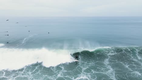 drone view of an unrecognizable surfer dropping into a wave in oceanside california