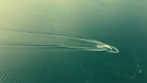 Vista-Aérea-Que-Muestra-Jetski-Flotante-En-El-Mar-Verde-Durante-El-Día-Soleado-En-Cámara-Lenta