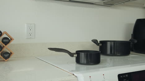 kitchen counter with two black pots and a spice rack, clean and organized