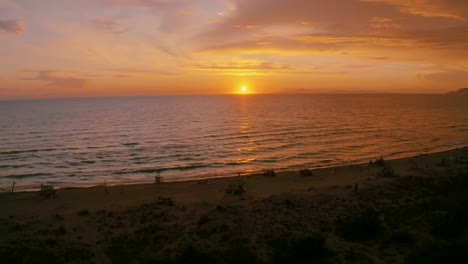 imágenes aéreas de la puesta de sol en una playa de arena a la orilla del mar en el icónico parque natural maremma en toscana, italia, con un espectacular cielo nuboso de tormenta y tipis de madera a lo largo de la playa vacía