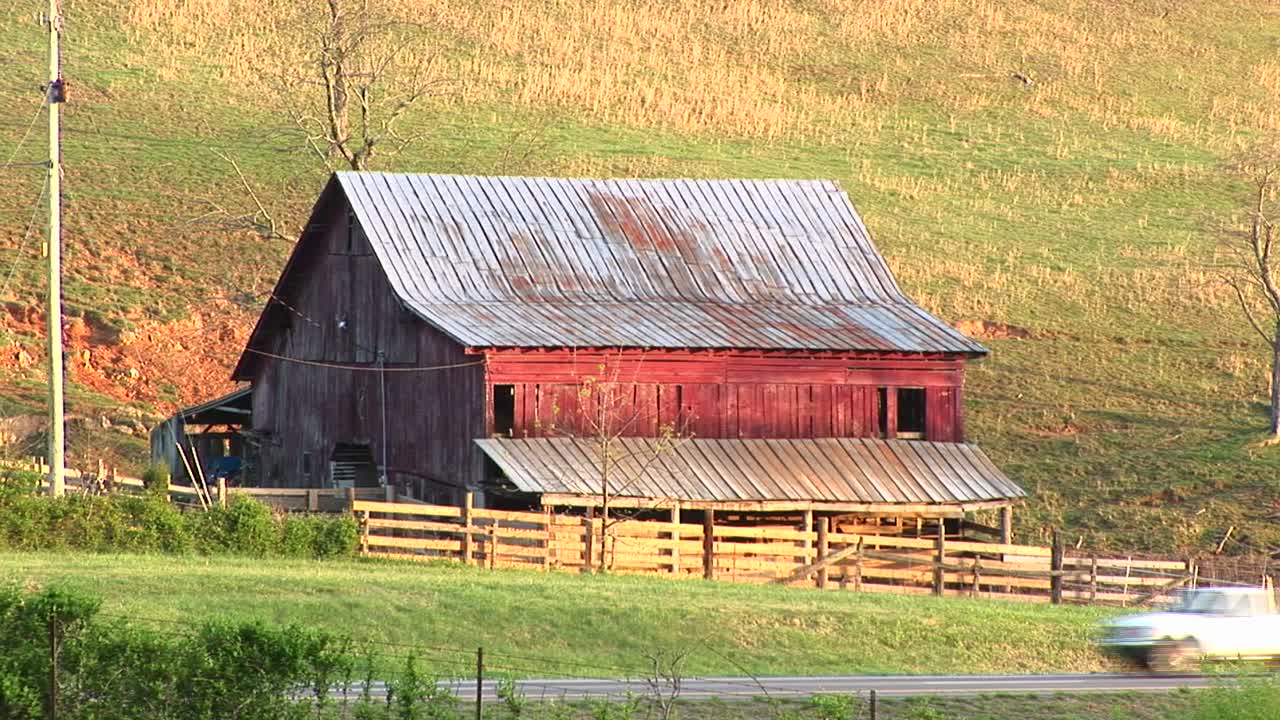 가족 농장의 죽음과 미국 역사의 전체 시대를 회상하는 오래된 버려진 농장 헛간과 린토를 자동차가 지나갑니다.