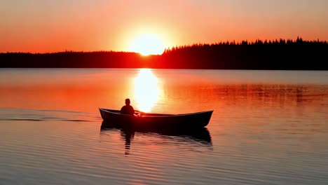 sunrise/sunset on a lake with a person rowing a canoe