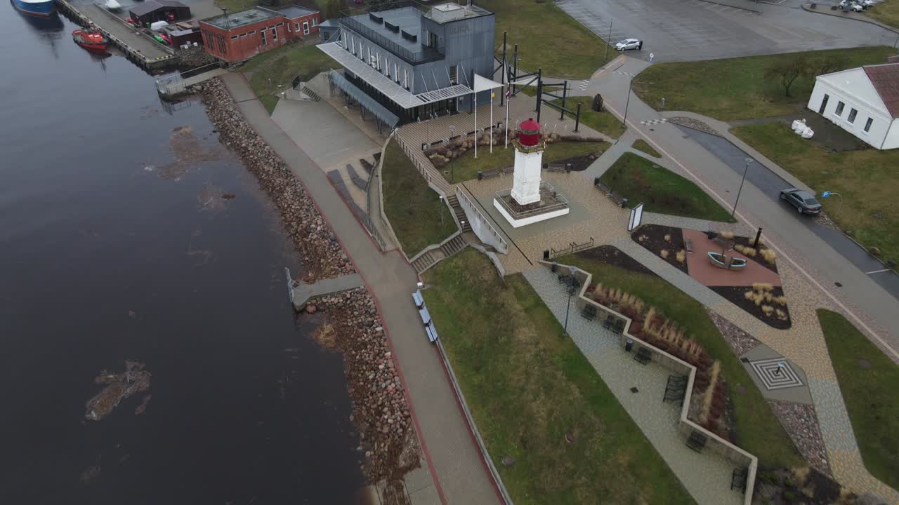 Aerial photograph of Salacgrīva, a coastal city in Latvia, featuring residential buildings, industrial areas, and a riverbank. Ideal for urban or geographical studies.
