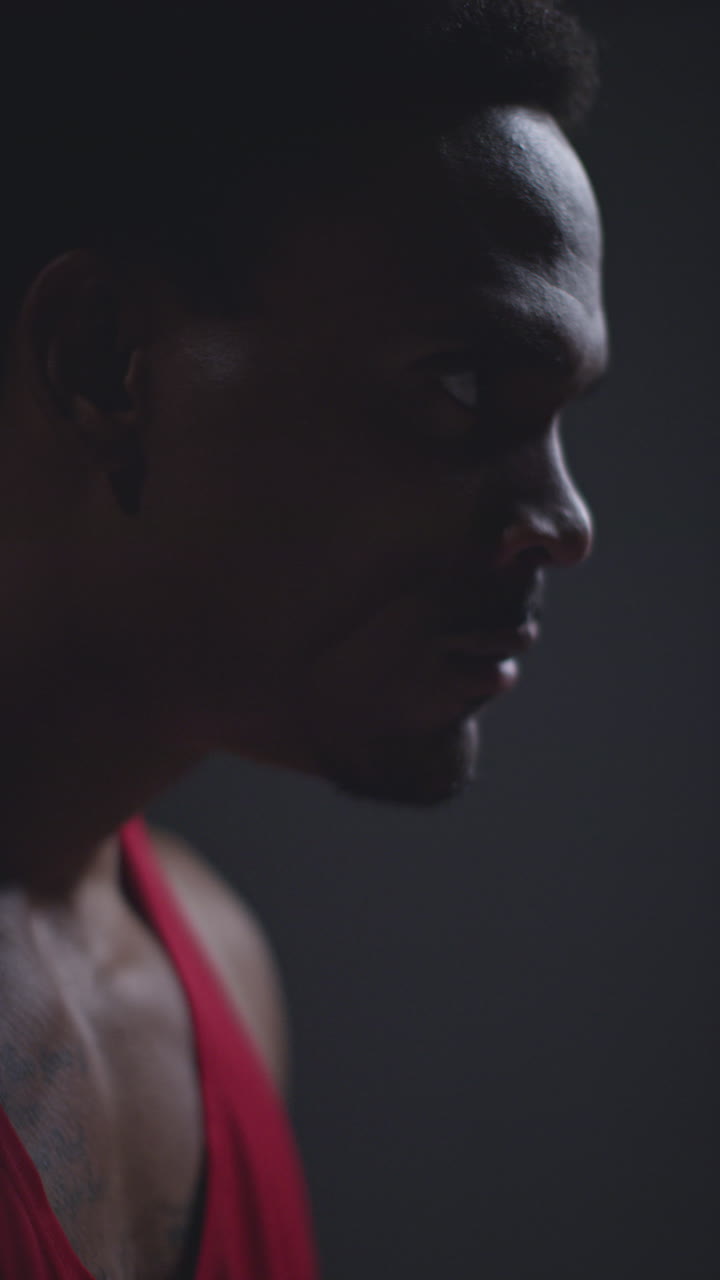 Vertical Video Close Up Profile Shot Of Determined Male Boxer Or Athlete Training In Gym Preparing For Fight Or Sports Event Against Black Studio Background