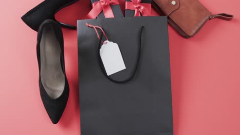 video of gift bag, gift boxes with red ribbon, shoes, purse and copy space on red background