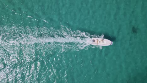 aerial view of a boat speeding through clear turquoise ocean water
