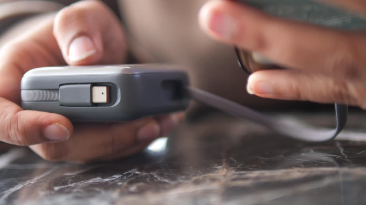 Primo piano di mani che ricaricano uno smartphone con un power bank