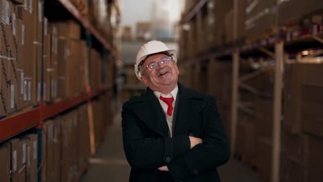 old solid man in a business suit with a helmet on his head looks at the camera and smiles