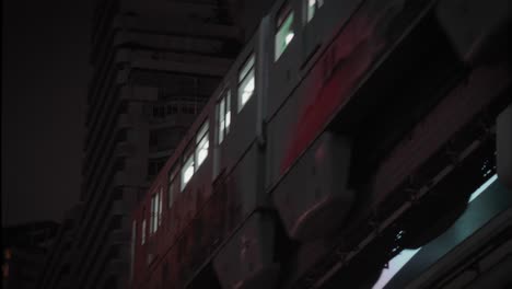 above ground railway car or metro line travels across night sky illuminated by full moon by the skyscraper