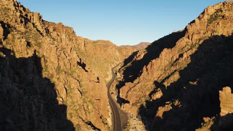 4k aerial of a drone flying over a winding road in between the mountains in superior arizona at golden hour east of queen creek tunnel on highway 60