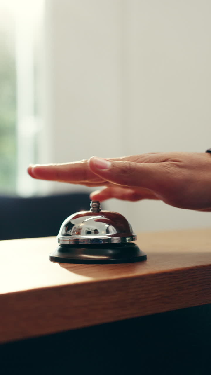 Mano che suona il campanello di servizio sulla reception per richiedere assistenza