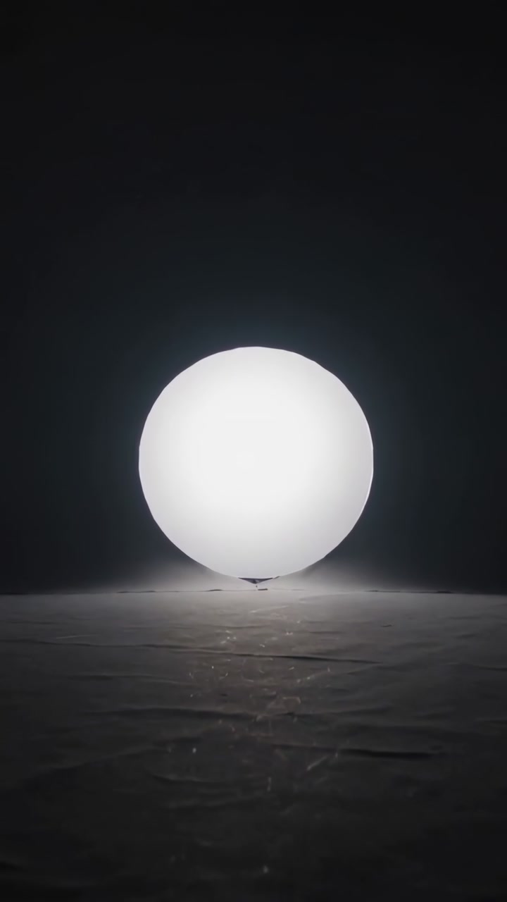 Vertical video: Glowing white sphere rising off dark knot in dark studio after halo widening