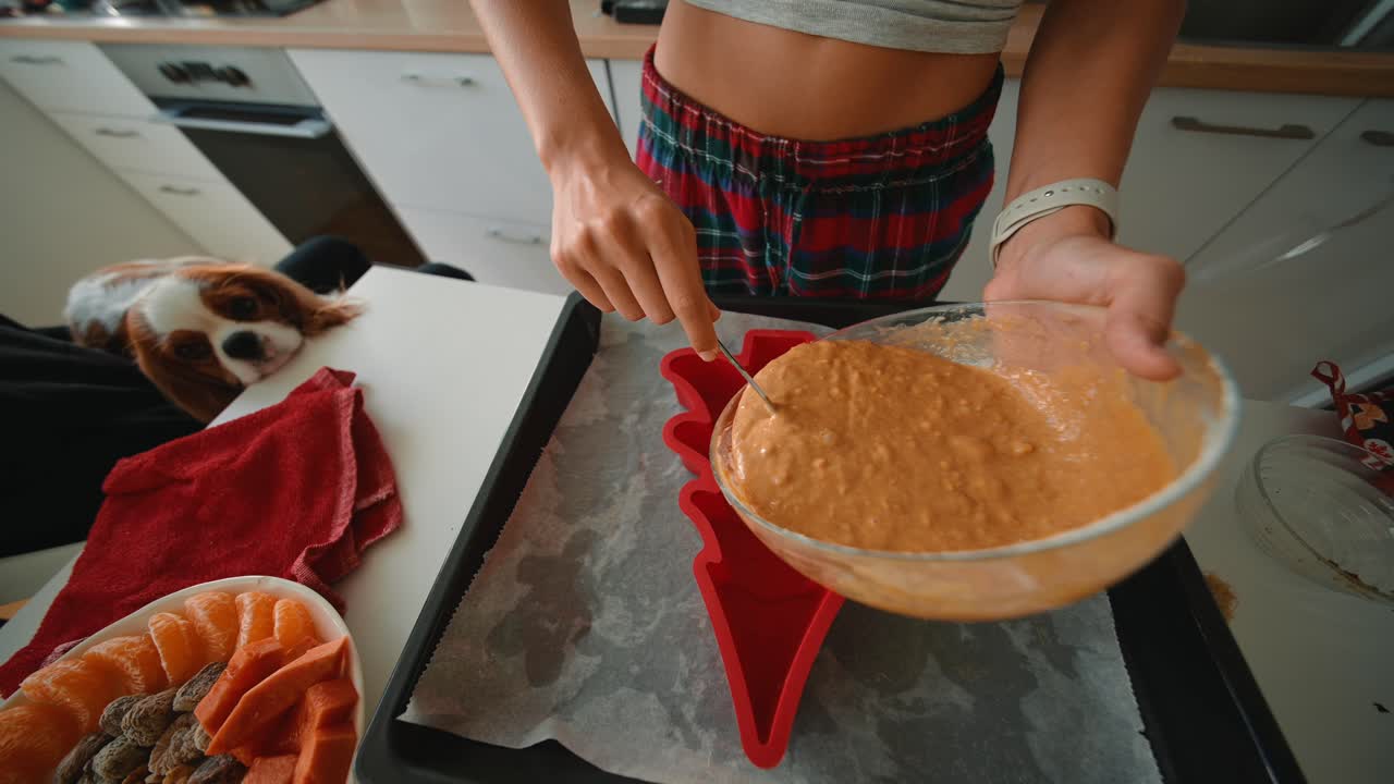 Person baking with a dog nearby